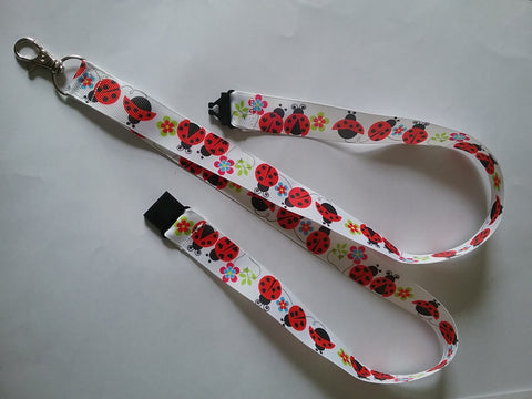 Lanyard made with white ribbon with lots of red ladybirds as the pattern it has a safety breakaway lanyard id or whistle holder